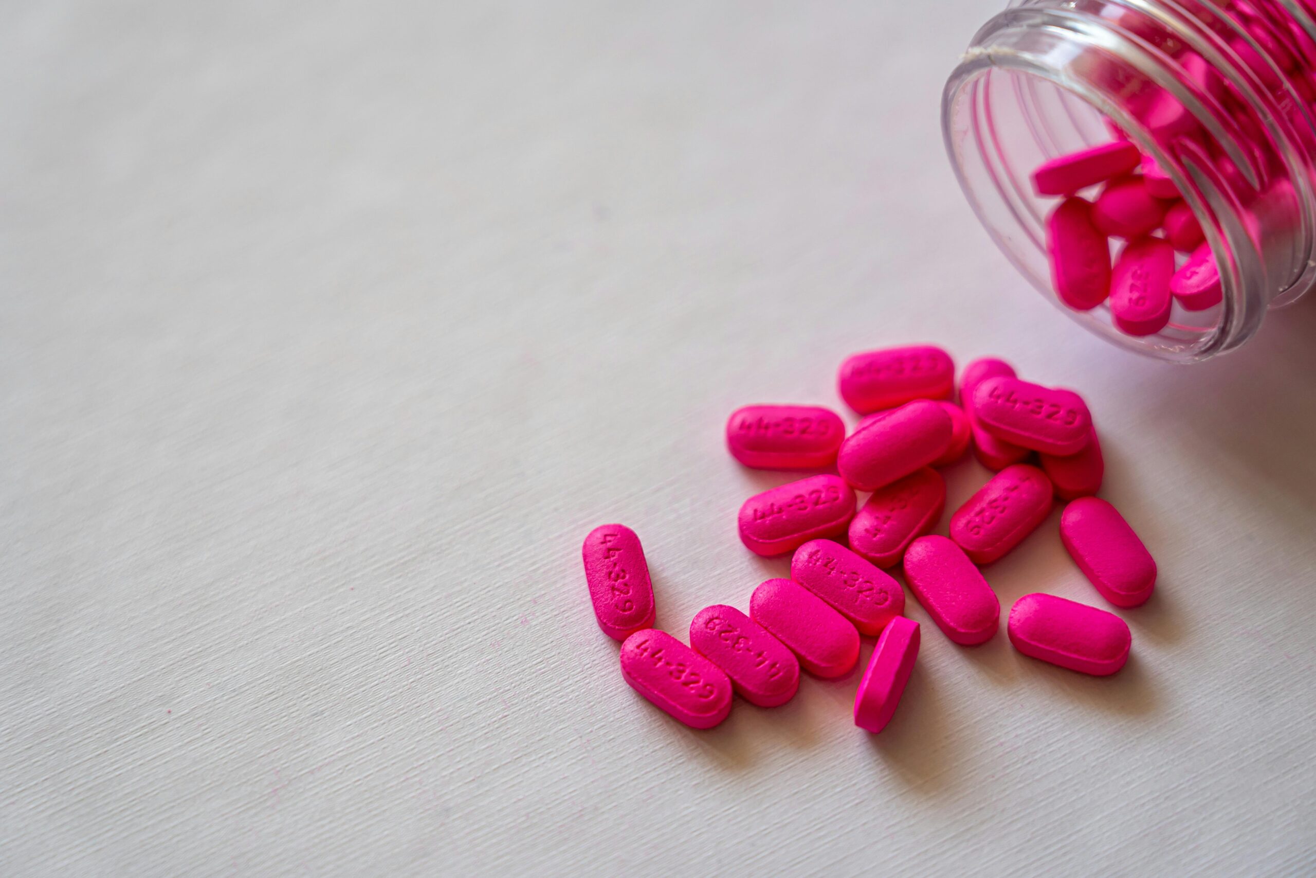 Pink supplement tablets scattered on a table.