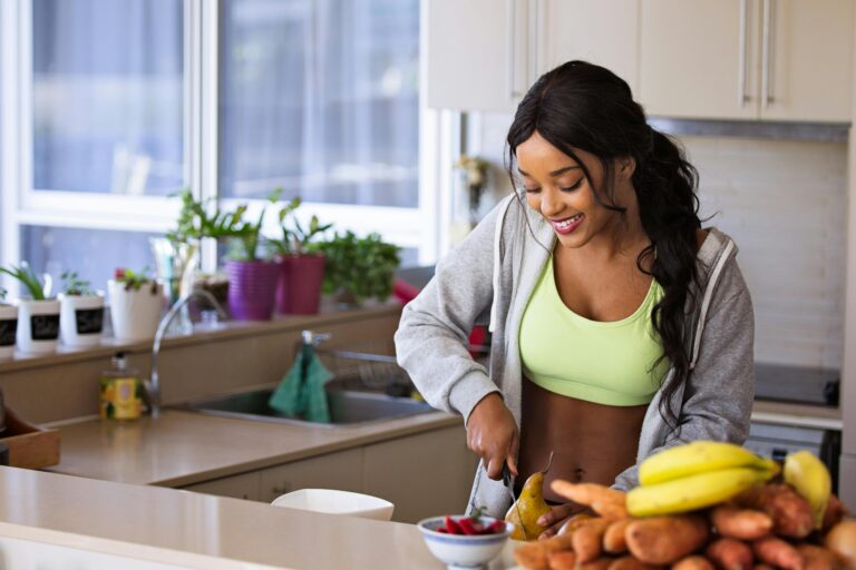 Smiling woman cutting fruit in her kitchen, highlighting a healthy lifestyle.