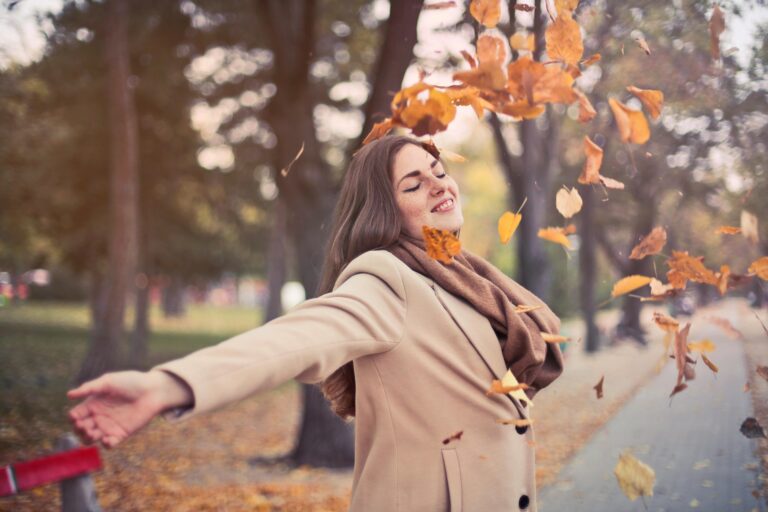 Smiling woman standing in autumn with falling leaves