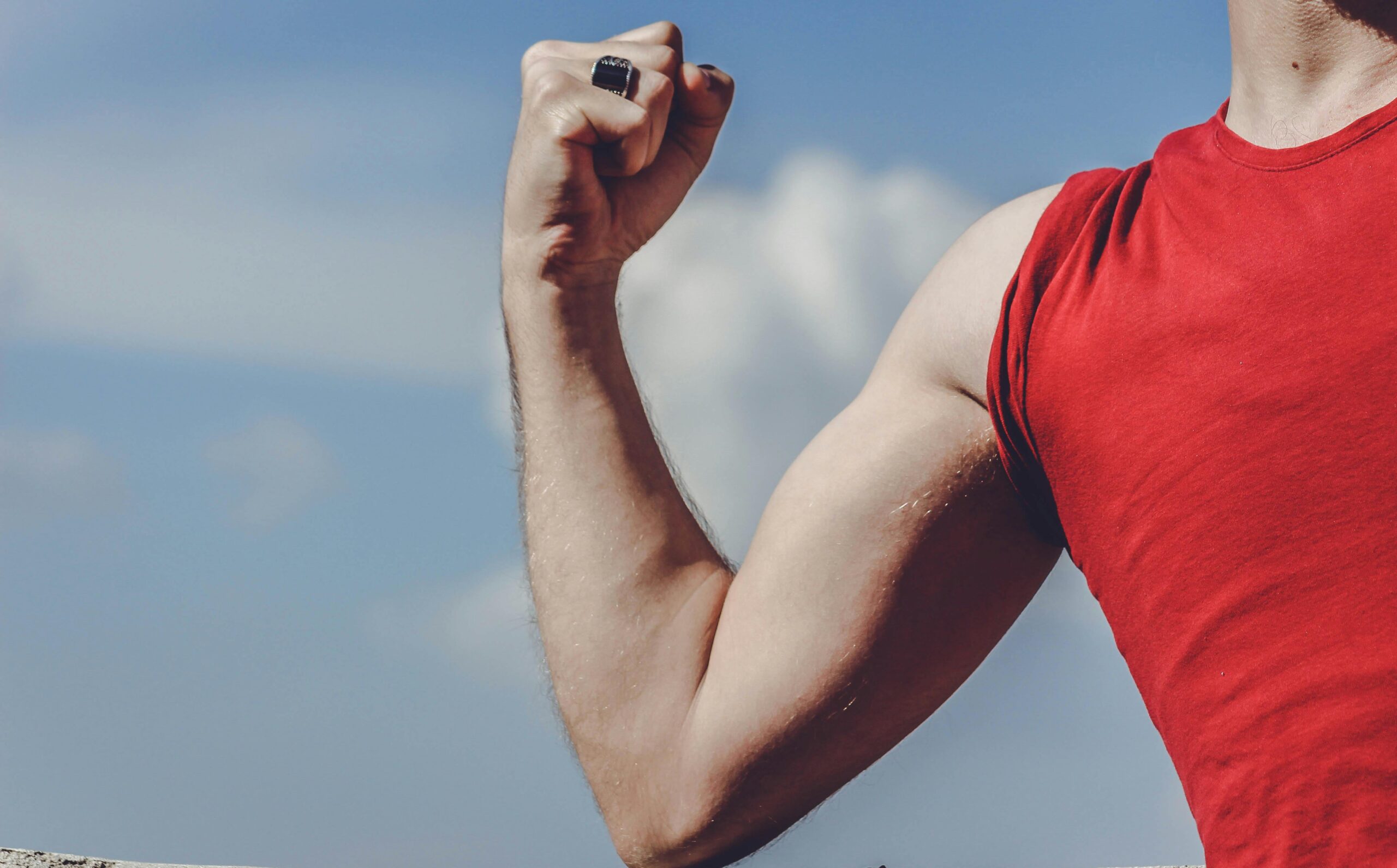 A strong man's arm flexing, wearing a red shirt.