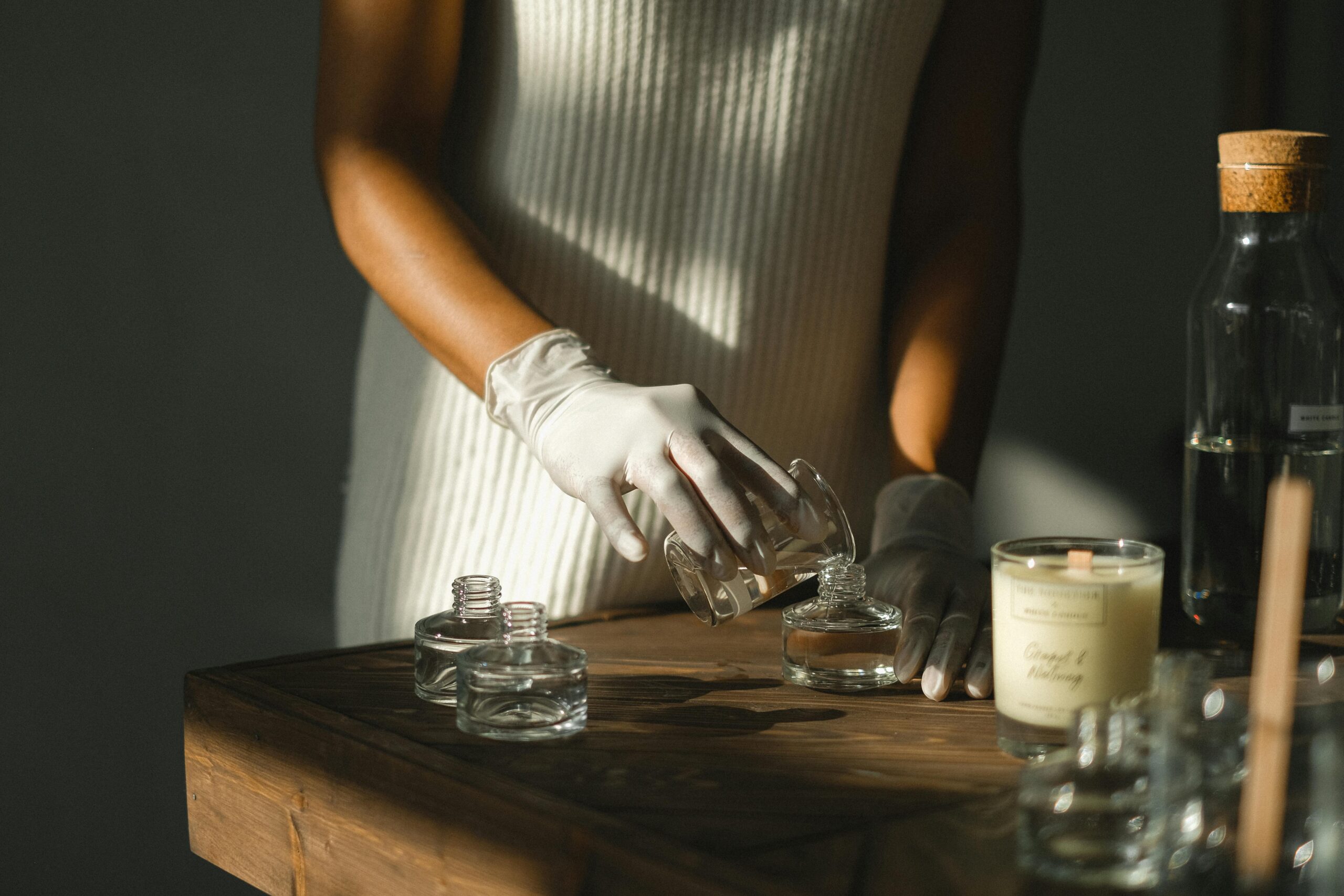 A girl making her own essential oil candle at a table, surrounded by candle-making supplies