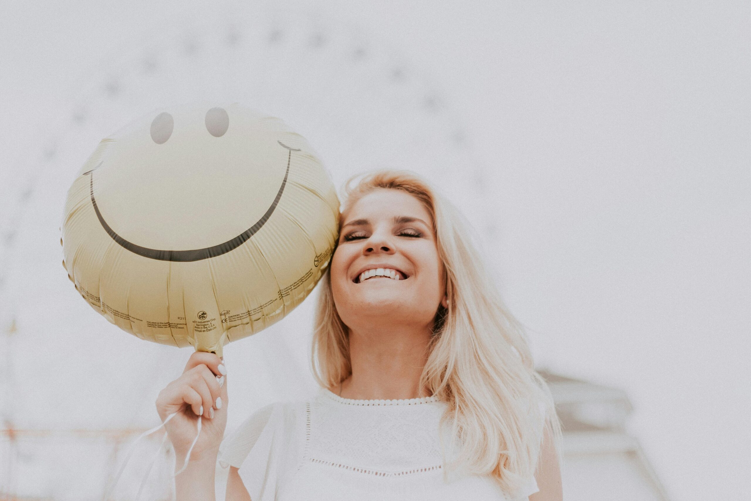 Woman smiling while holding a balloon with a smiley face