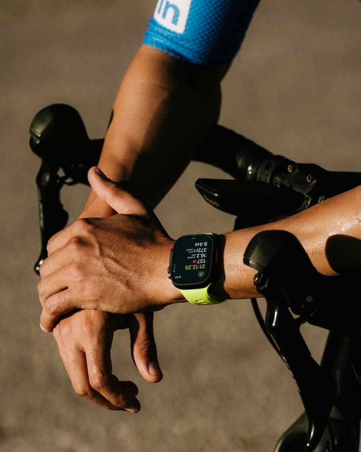 Close up of man cycling, showing wrists and wearing a smart fitness watch