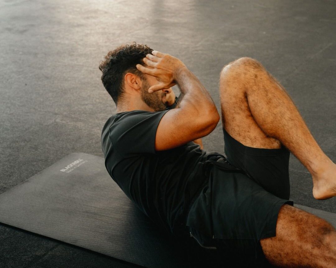 Man on an exercise mat doing bicycle crunches.