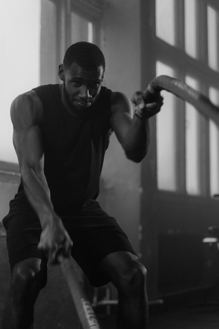 Focused man in gym intensively training with ropes indoors working on his gains.
