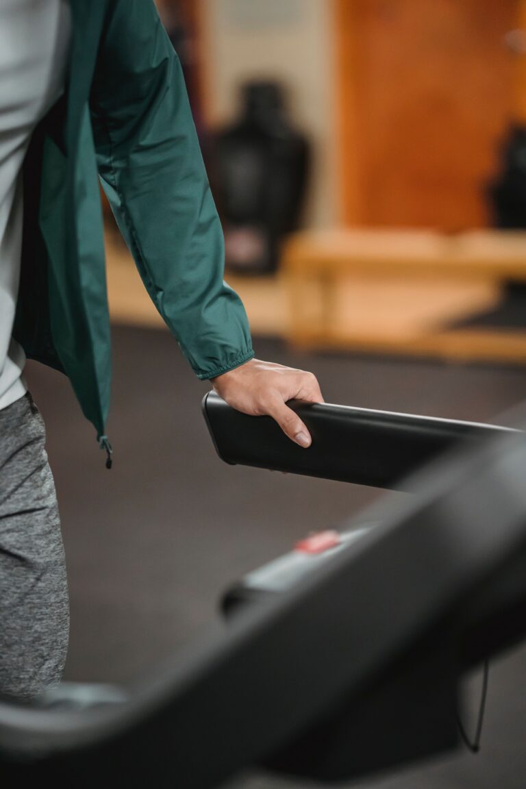 male running on contemporary treadmill on blurred background of sport club