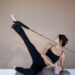 Woman using reformer machine and wearing a Pilates workout set.