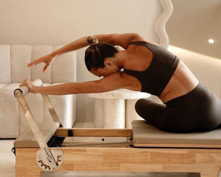 Girl using Pilates reformer machine and stretching